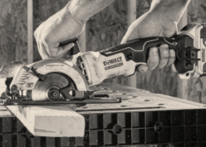 hands holds a dewalt cordless circular saw and using it to cut a piece of wood for a tool promotion