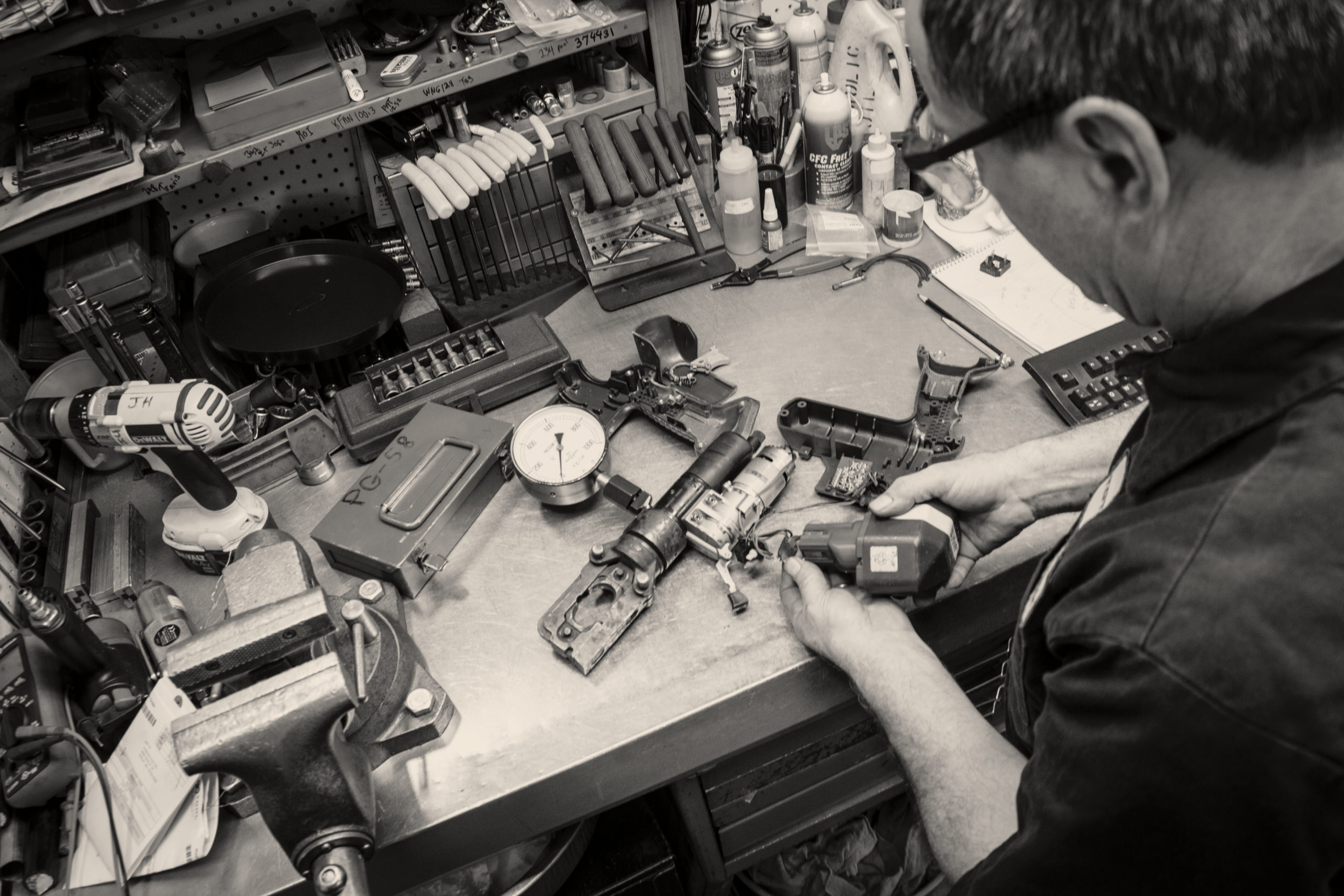 man conducting industrial tool repair on a worktable